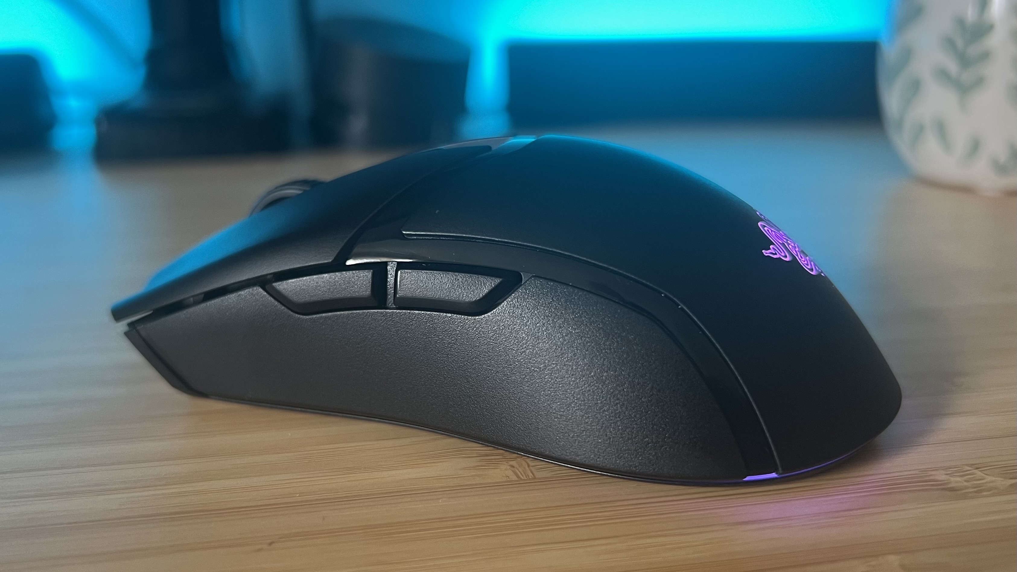 Side view of Razer Cobra Hyperspeed gaming mouse on a wooden desk with blue backlighting