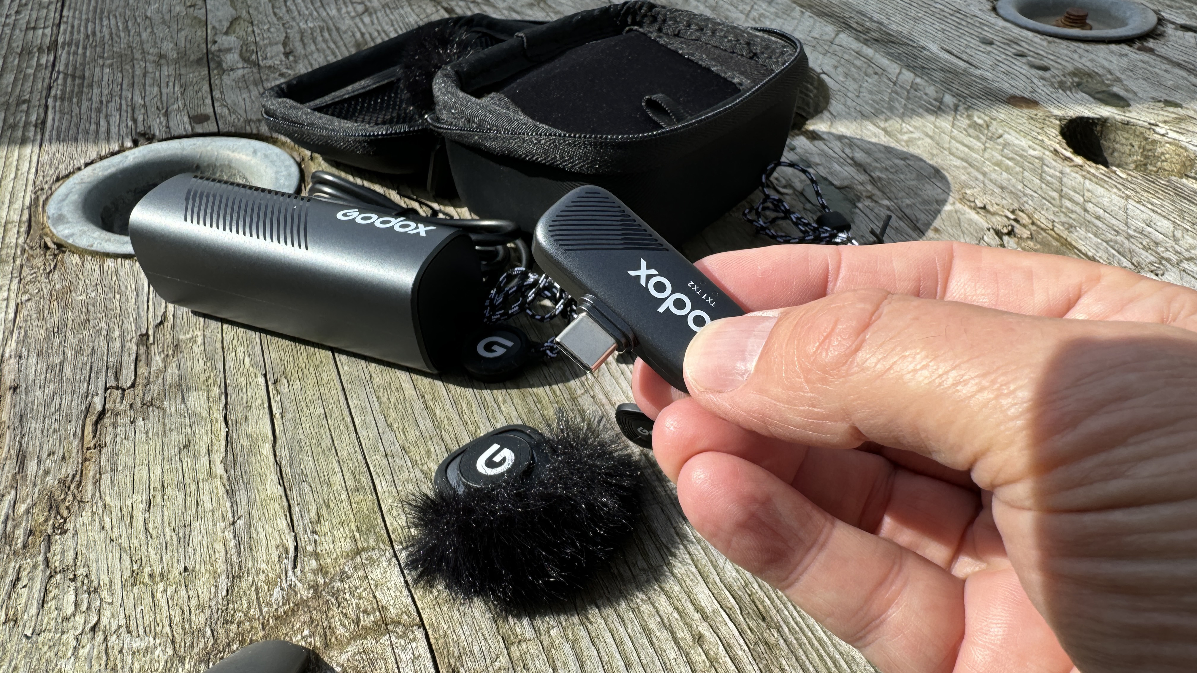 Godox Cube-SC microphone held in a hand over a wooden surface