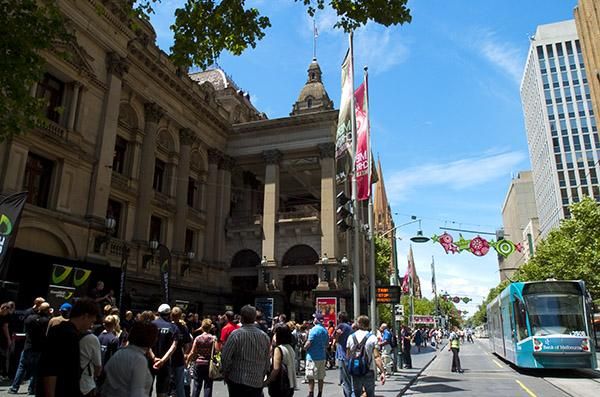Bystanders and trams make their way around the GreenEdge function on Melbourne's busy Swanston Street.