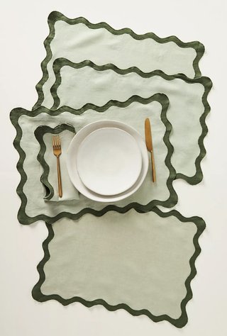 four wavy place mats stacked on top of each other with a set of plates and cutlery on top