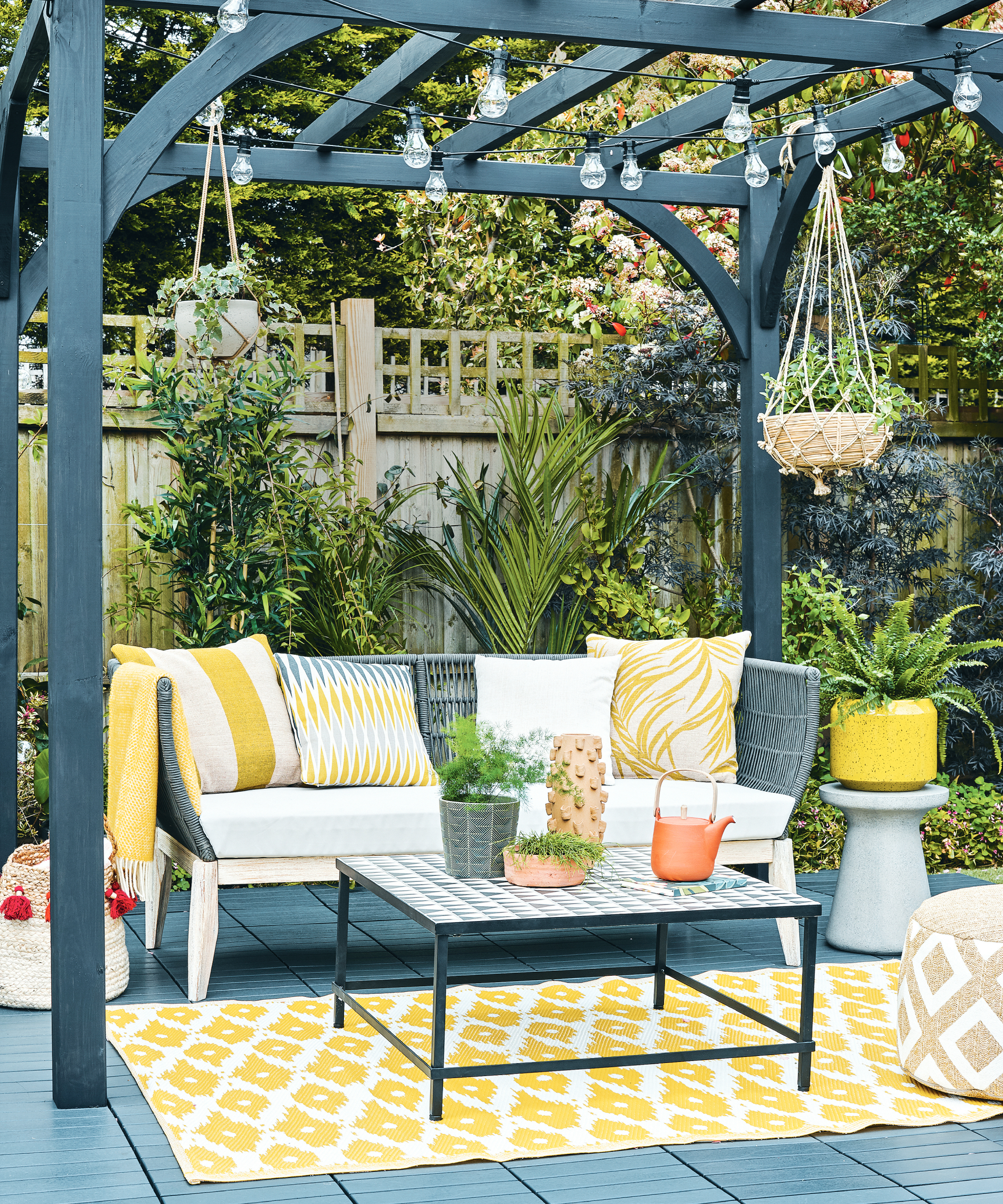 Accent yellow color used on garden patio with cushions, planters and a rug.
