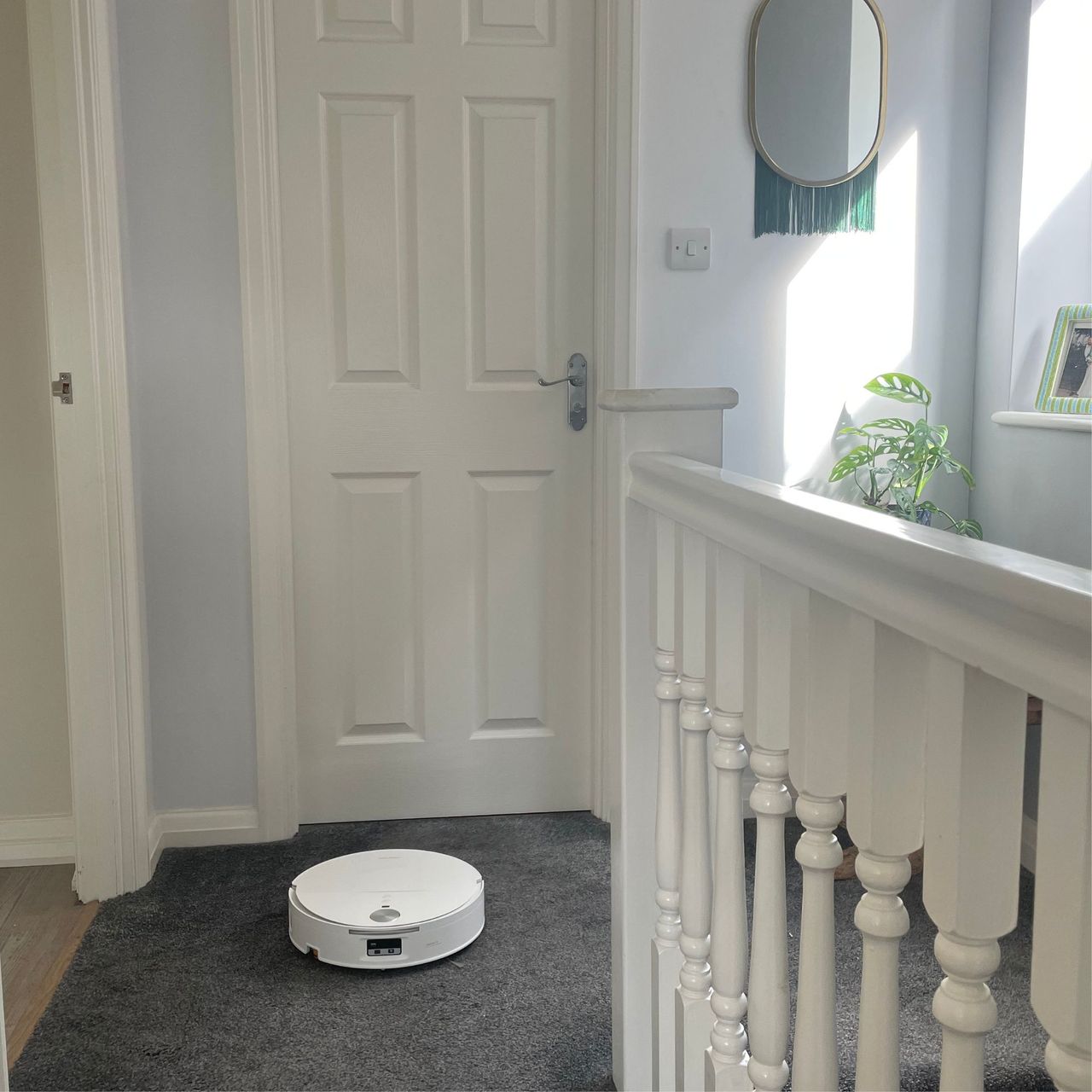 Roborock Qrevo Edge 2 Flow Robot Vacuum sitting on grey carpet on a landing with a white door behind it