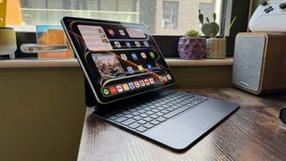 An Apple iPad Pro connected to a keyboard case and sitting on a wooden desk.