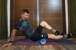 Image shows a cyclist using a foam roller.
