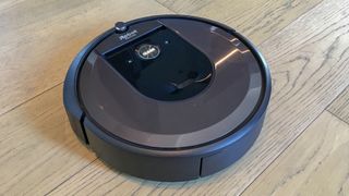 En irobot roomba i7+ står på ett trägolv