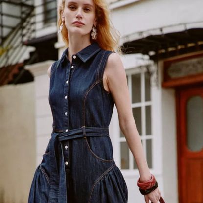 Young woman in denim dress next to red door