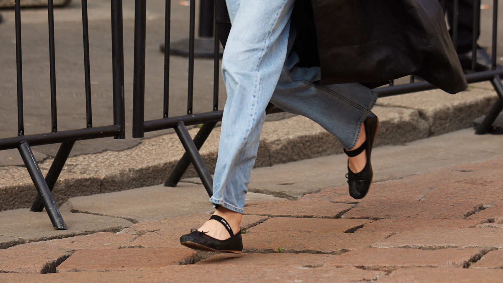 Woman wearing light-wash jeans and black flats. 
