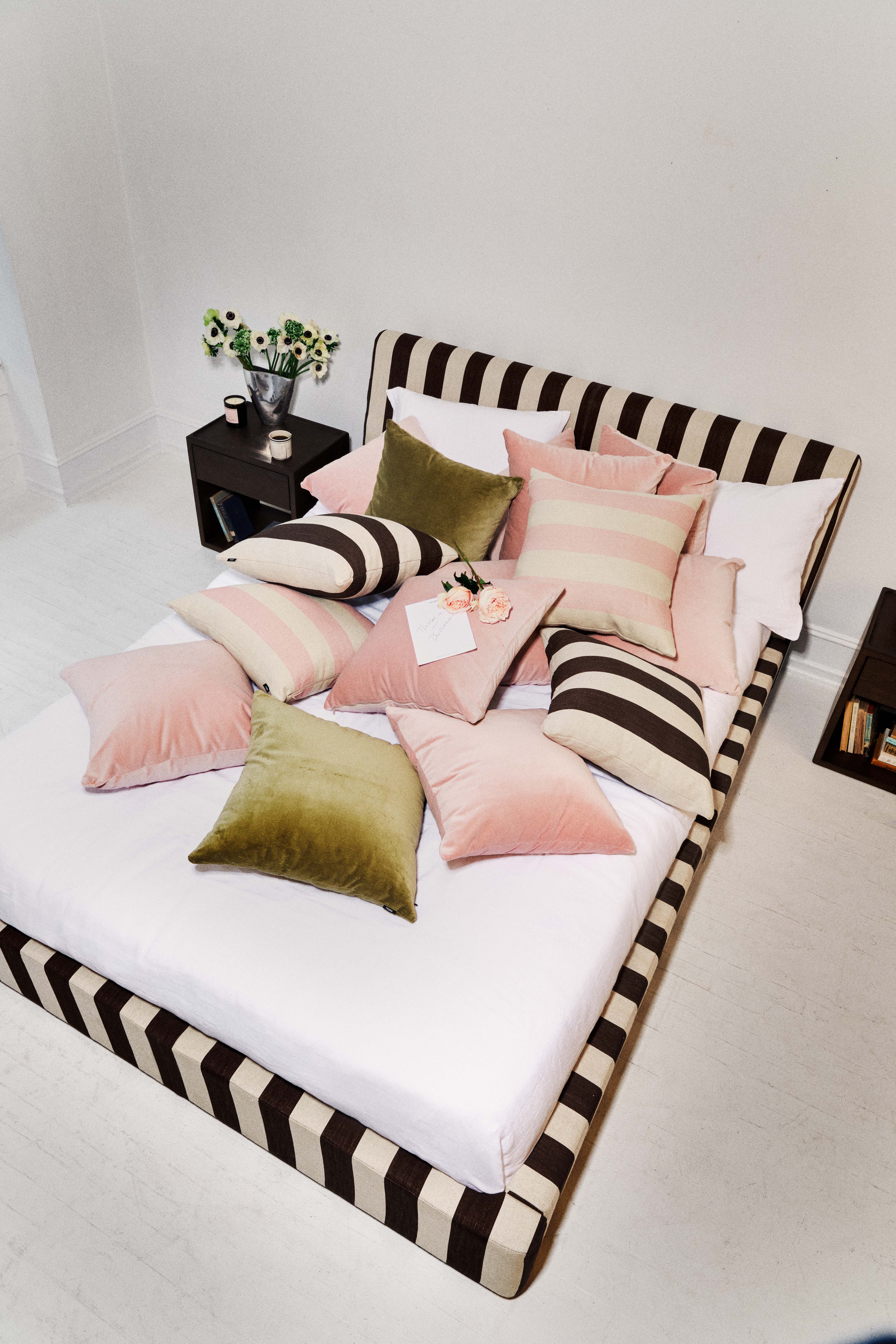A striped bed is topped with pillows in pink stripes and soft greens.