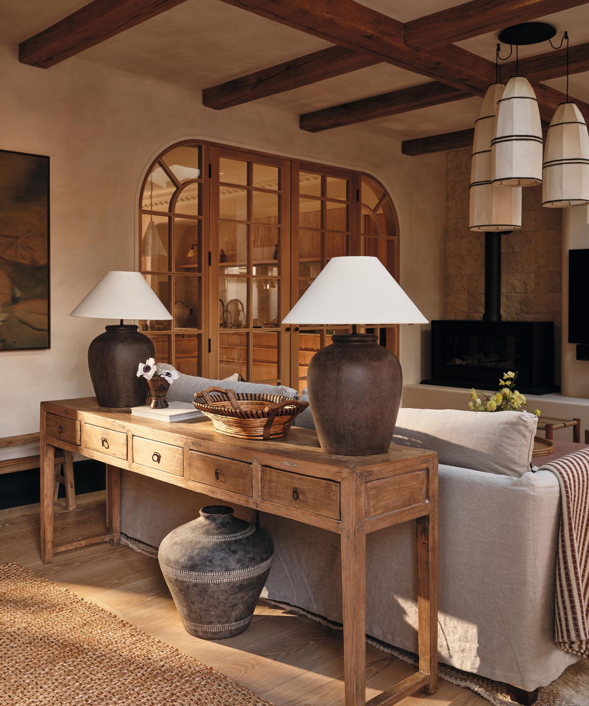 a limewashed large extension living area with arched oak and glass doors, ceiling beams and rustic wooden console