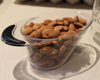 A measuring jug of raw almonds on white countertop