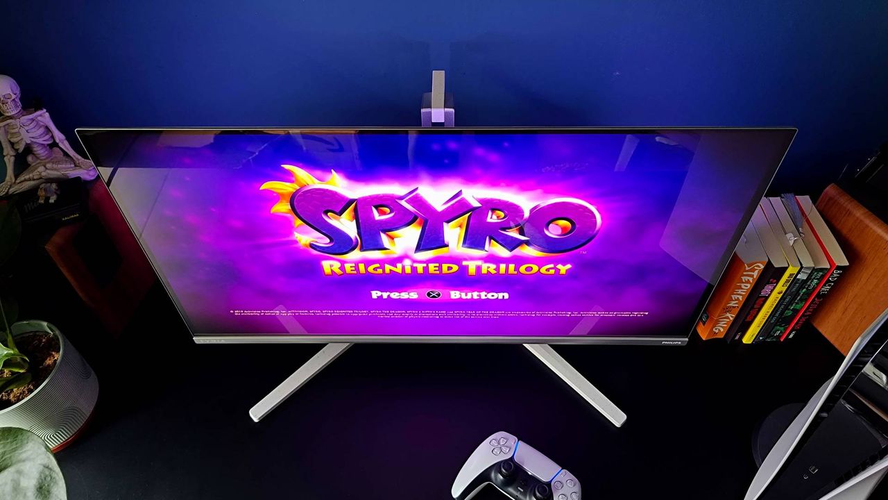 Downward view of Philips Evnia 32M2N8900 monitor with Spyro Reignited Trilogy splash screen displayed.