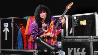 Bruce Kulick plays a garish Superstrat whilst seated on some Kiss-branded flight cases