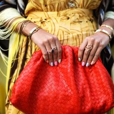 model with spring nail colors against a red handbag