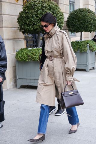 Kendall Jenner wears a double belted trench coat and jeans with heels from The Row