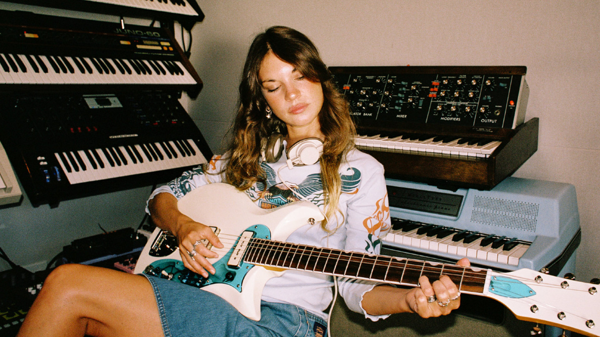 songwriter amy allen sits in a studio around keyboards and playing the guitar