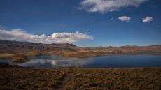 A scenic photo of the Andean plateau with a lake and mountains in the background 