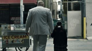 Kingpin holds a young Maya Lopez's hand as they walk in Marvel Studios' Echo