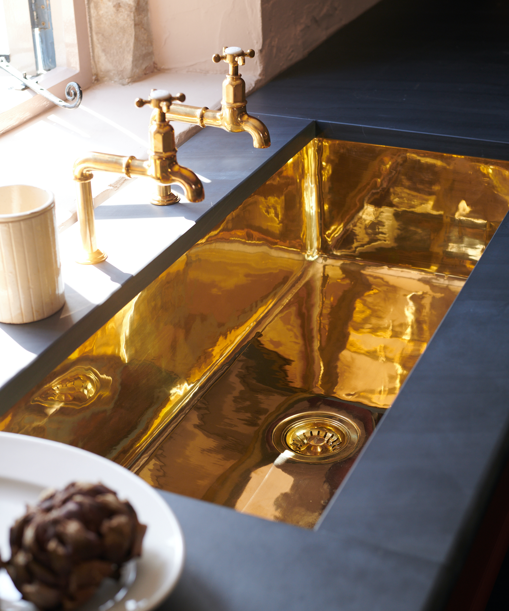 copper sink in black slate worktop with pillar taps