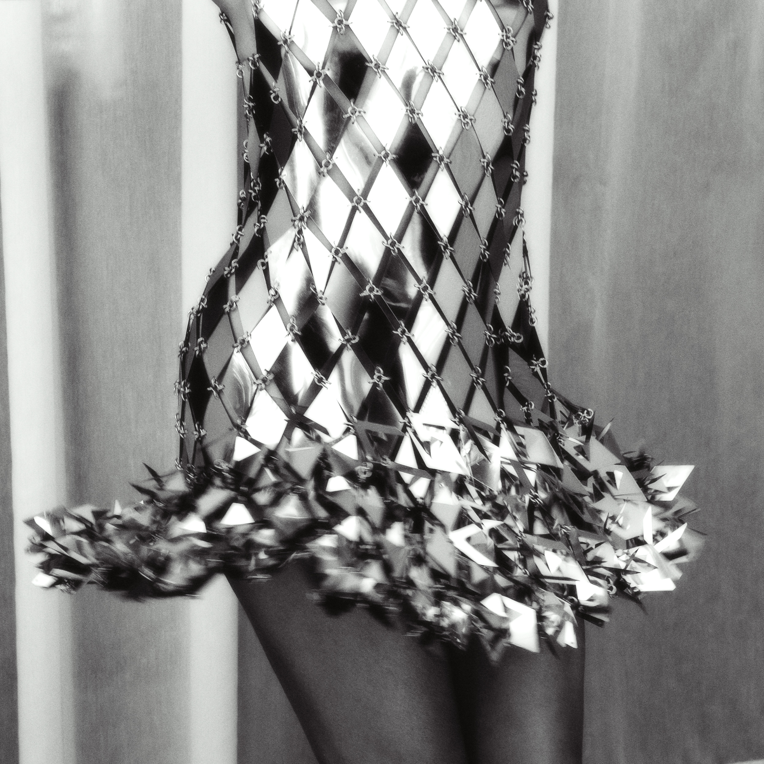 Fotografía en blanco y negro de Rachel Hilson moviéndose con su vestido de Rabanne compuesto por discos metálicos geométricos.