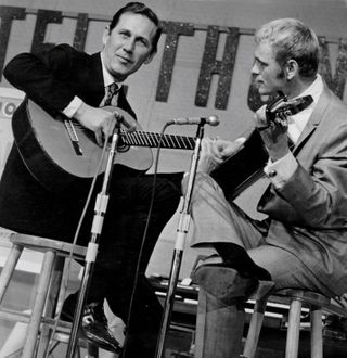 Guitarists Chet Atkins (l) and Jerry Reed (r) perform together onstage on acoustic guitars at a telethon in circa 1970.