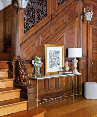 staircase in living room with original dark wood paneling and modern console table