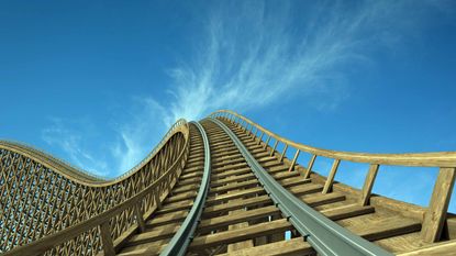 wooden roller coaster heading up into blue sky
