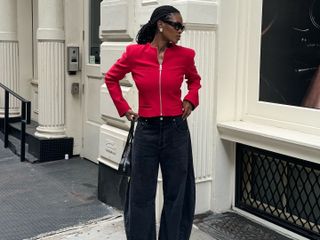 London woman wears a red zip up cardigan, black Citizens of Humanity barrel jeans, pointy toe heels and black sunglasses in New York.