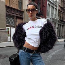 @aishafarida wears bootcut jeans with a graphic tee and a fur jacket
