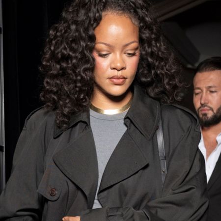 rihanna wears a black trench coat, gold necklace and gray tee.