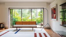 bauhaus style living room with large windows, couch, curved floor lamp and striped rug