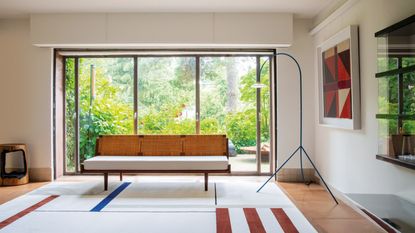 bauhaus style living room with large windows, couch, curved floor lamp and striped rug