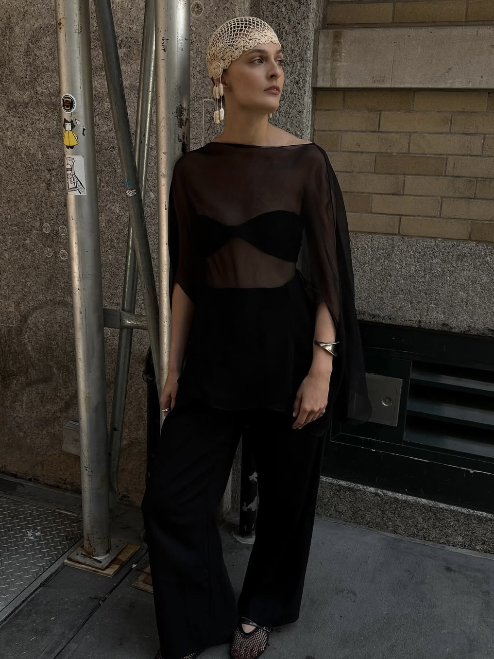Christie Tyler wearing a sheer top and black trousers.