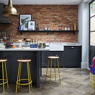 Kitchen with skylight, parquet floor and brick feature wall, and door into the garden, butler's sink and dark blue cupboards