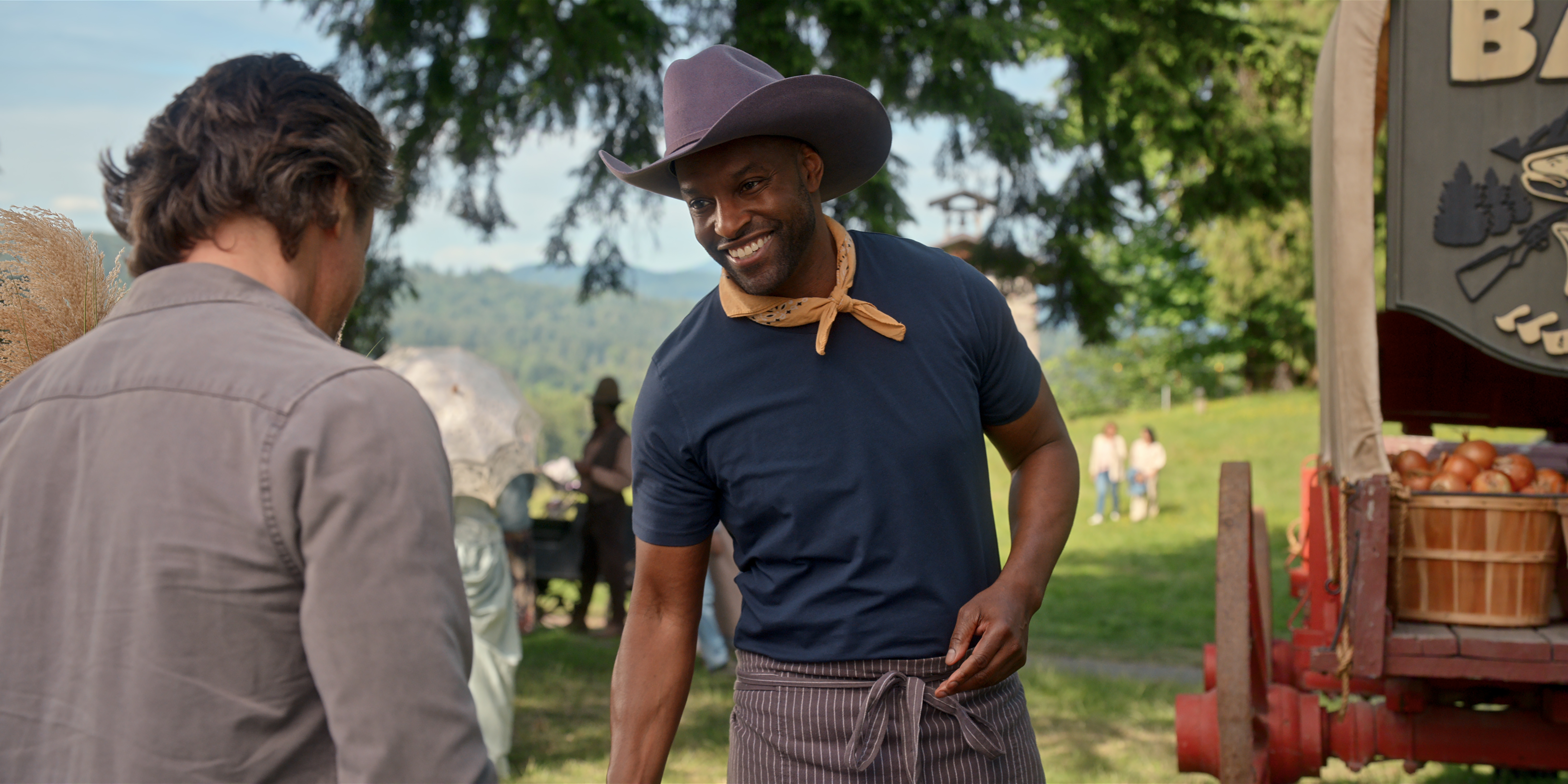 martin Henderson as Jack Sheridan and Colin Lawrence as John 'Preacher' Middleton at an apple stand at an outdoor event in virgin river season 7