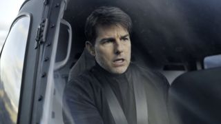 Tom Cruise, dressed in nothing but black sits behind the controls of a helicopter for Mission: IMpossible - Fallout (2018).