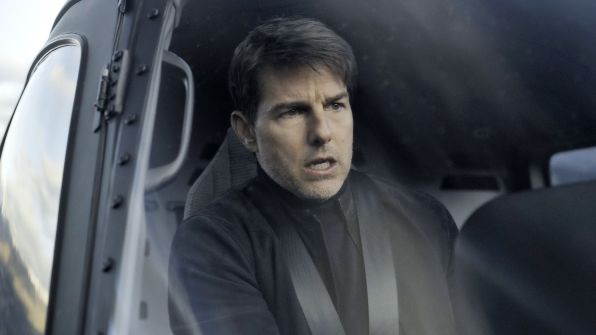 Tom Cruise, dressed in nothing but black sits behind the controls of a helicopter for Mission: IMpossible - Fallout (2018).