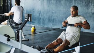 Cheap vs expensive rowing machine: Image shows man rowing in gym