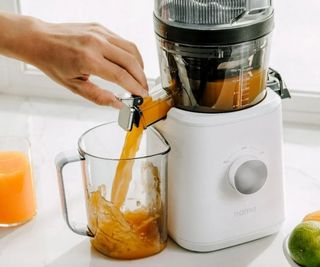 Jama J2 juicer with orange juice pouring out