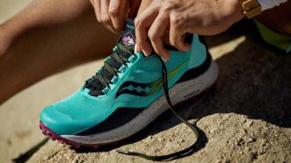 Woman putting on Saucony Peregrine 12 trail running shoe