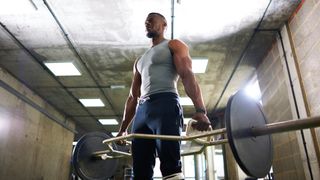Man in vest in gym performing trap bar deadlift