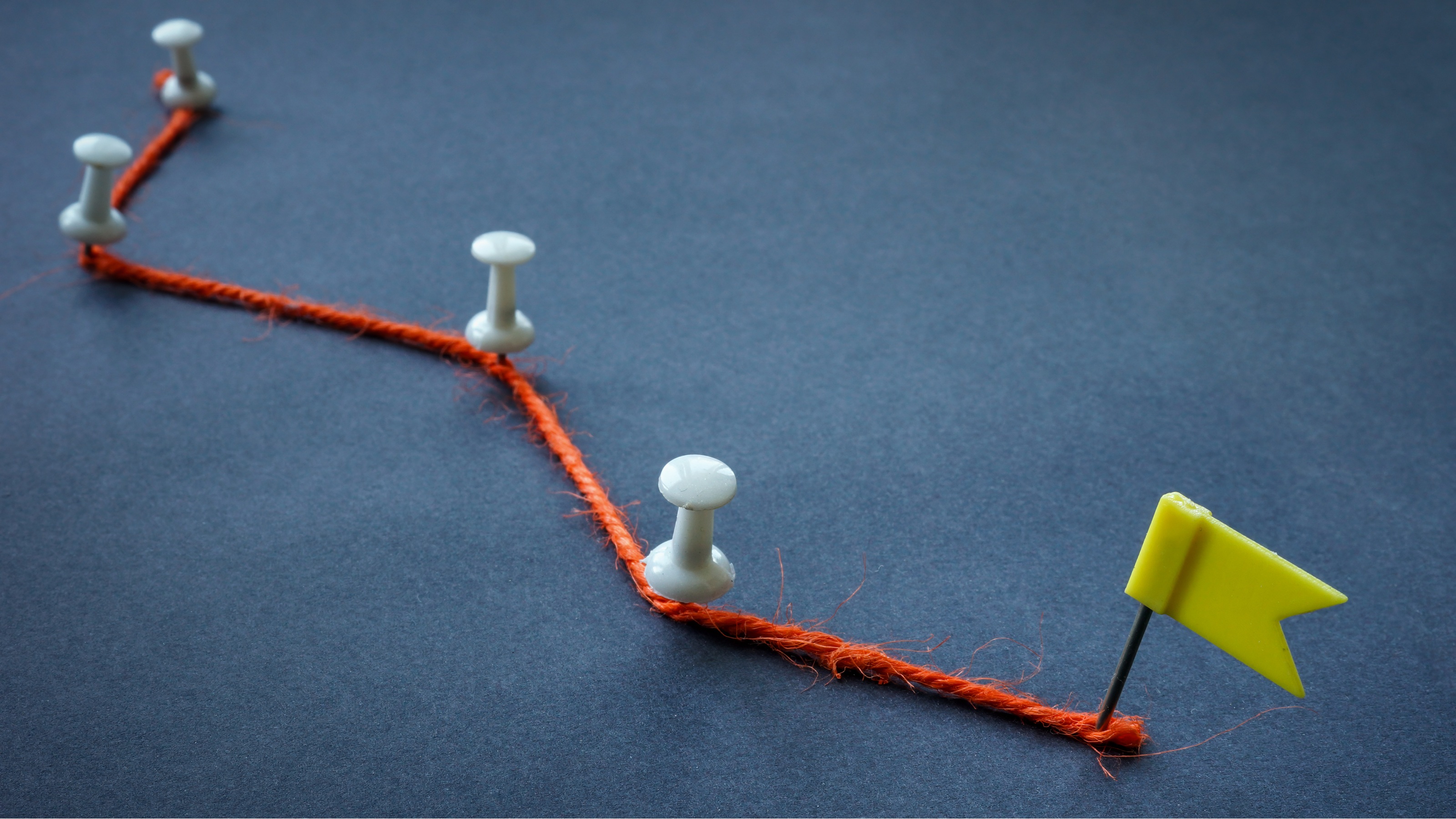 An orange thread stuck with pushpins leading to a flag, like it's an accomplishment.