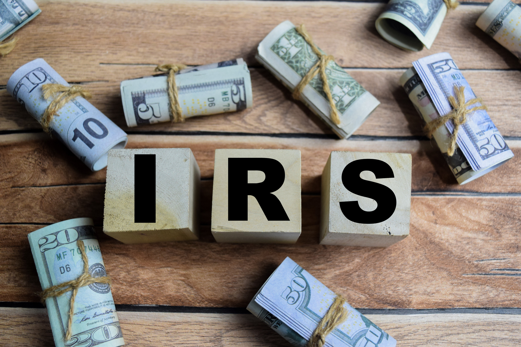 Concept word IRS - Internal Revenue Services on a wooden table with dollar bills