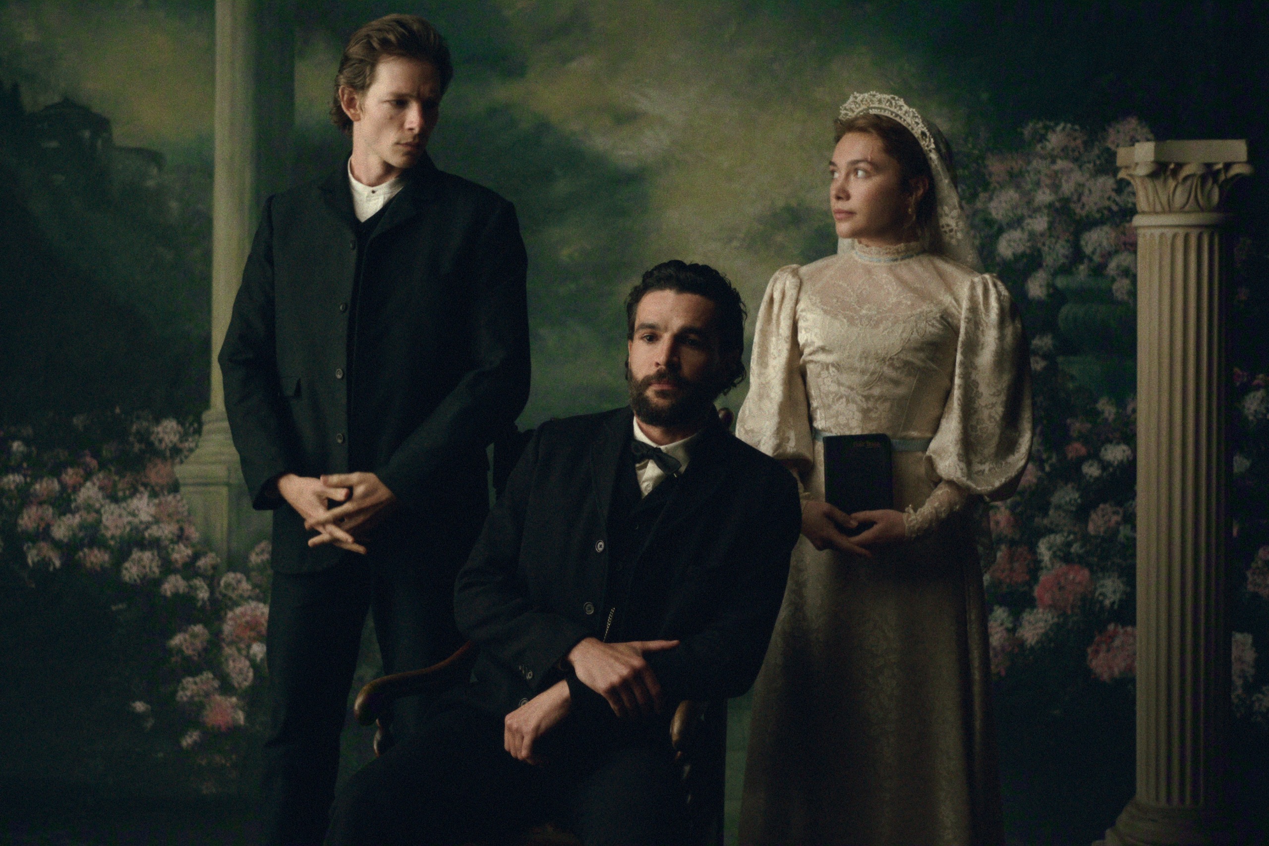 mike faist as charles looking at florence pugh as cathy as they pose standing behind a sitting christopher abbott as adam in an early 1900s photo studio in east of eden
