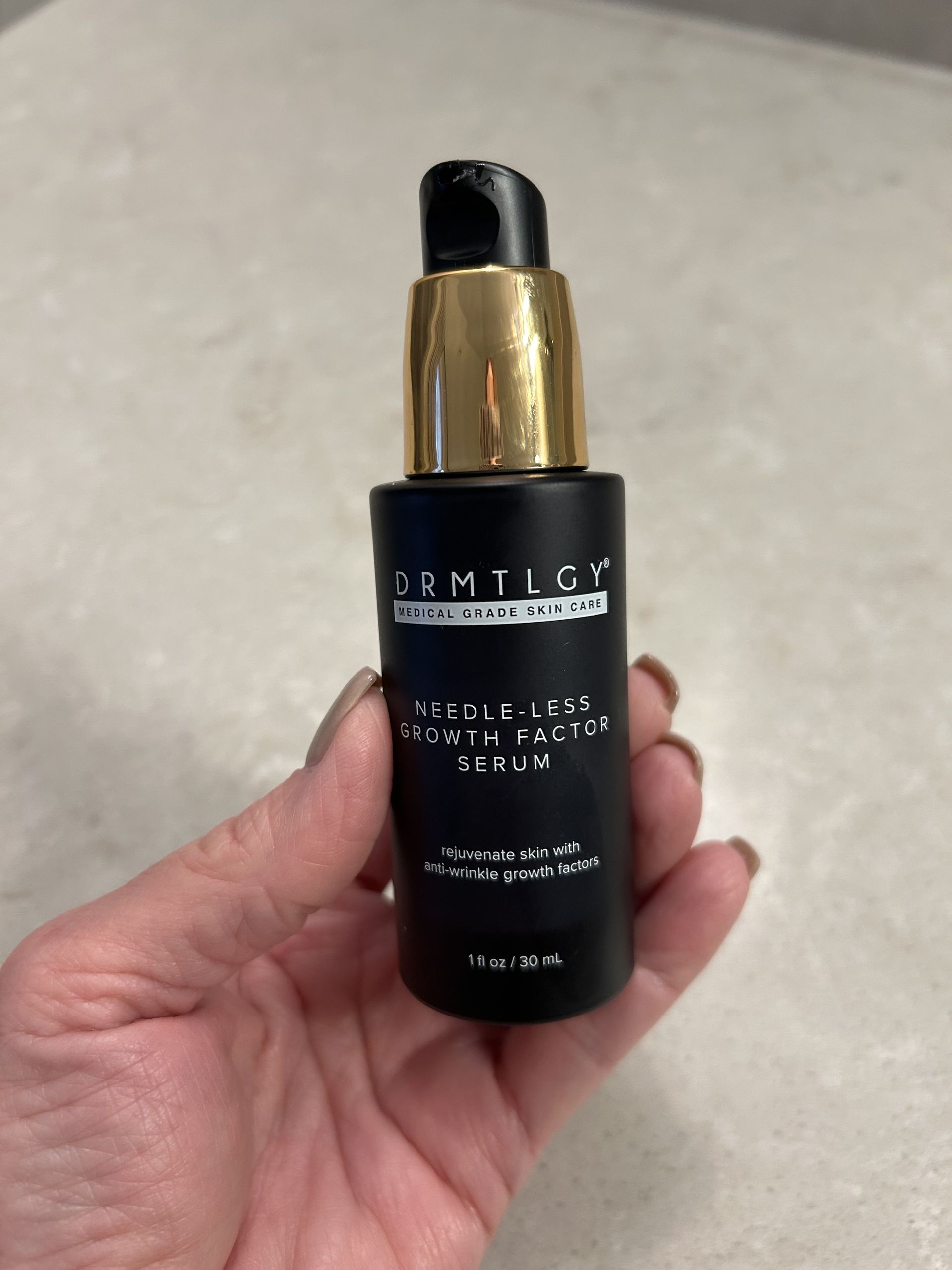 An image of Lori Brascia holding the Drmtlgy Needle-less Growth Factor Serum.