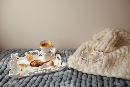 Cup with filter coffee, organic granola with honey on grey and beige wool merino giant plaid. Comfortable at home, happy mood and leisure cozy morning concept, hygge home decor