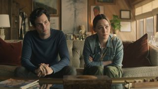 Joe and Love sit on a couch and talk to someone off screen in You season 3 on Netflix