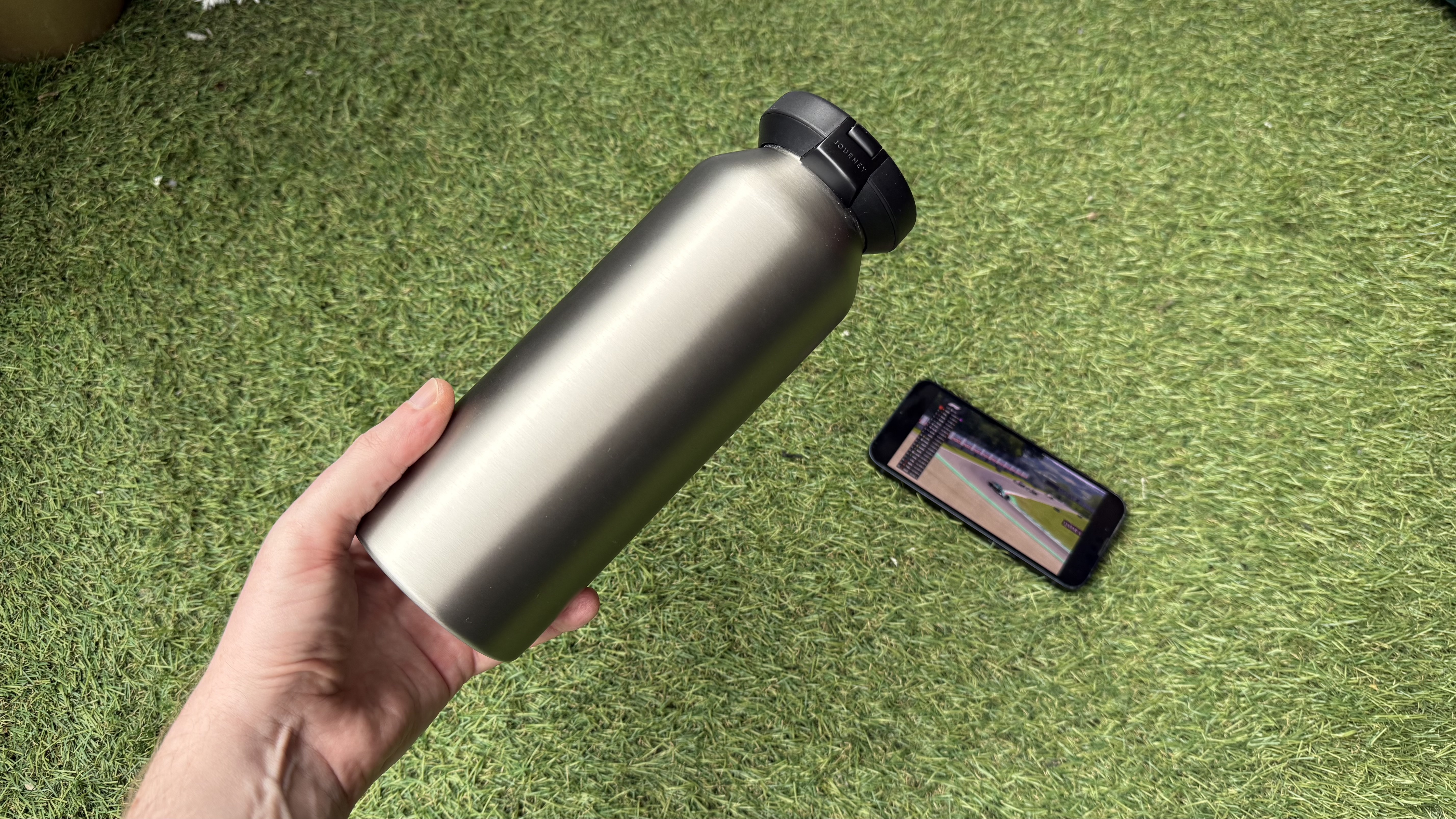 The Journey Reevus water bottle on a faux-grass surface