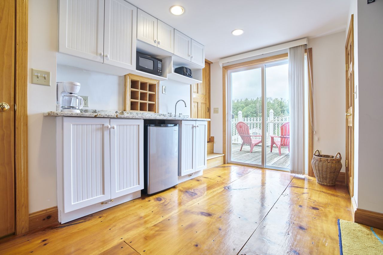 A dated morning kitchen with wooden floors and white cabinetry