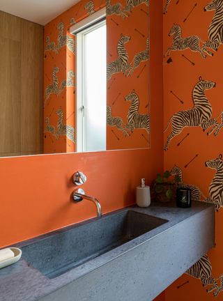 Bathroom with orange wallpaper and stone basin