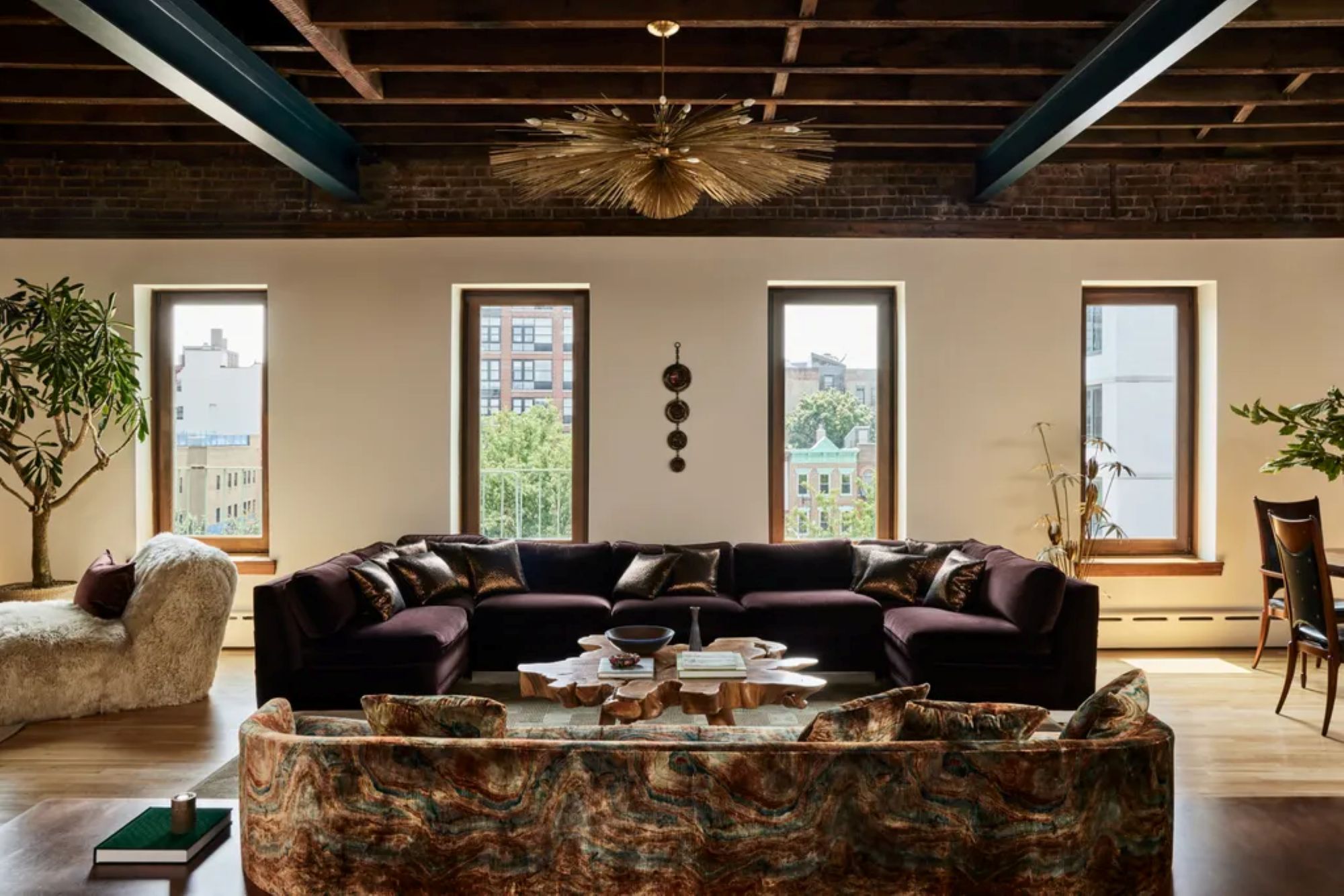 a living room with two couches facing each other, a large ceiling light, and four windows with no window treatments